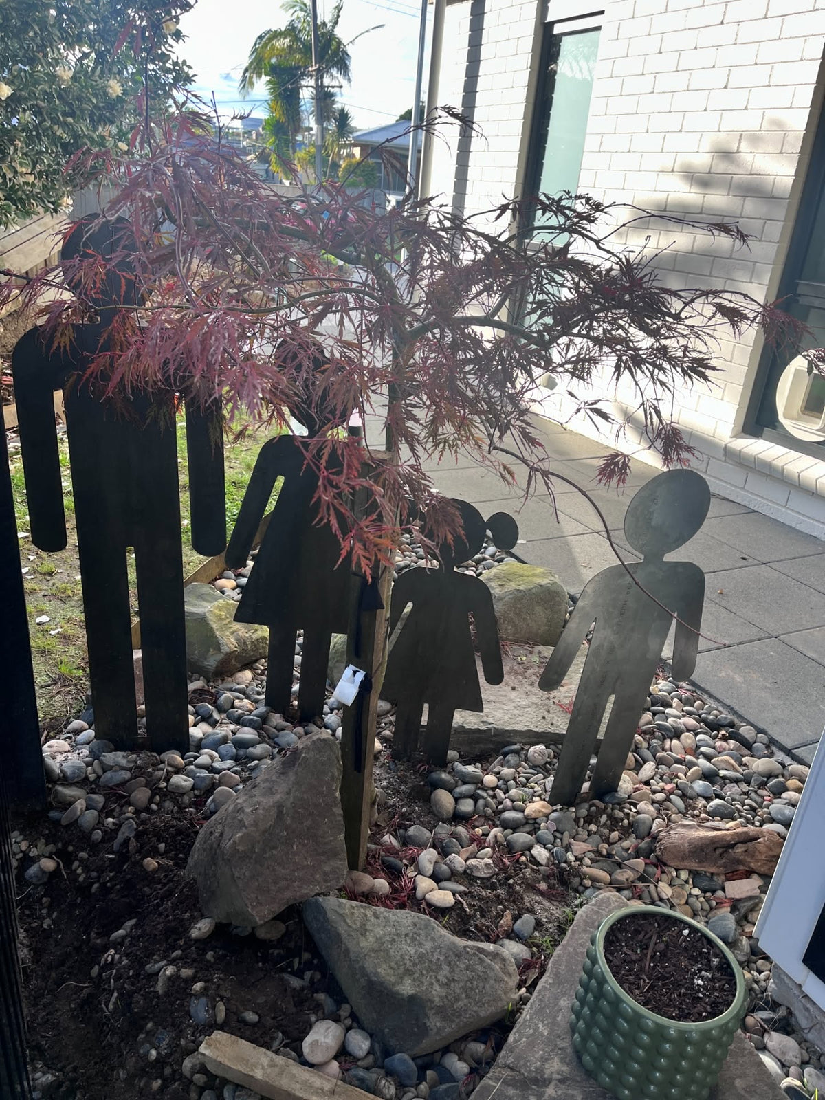 Corten steel family silhouettes in a rock garden next to a home